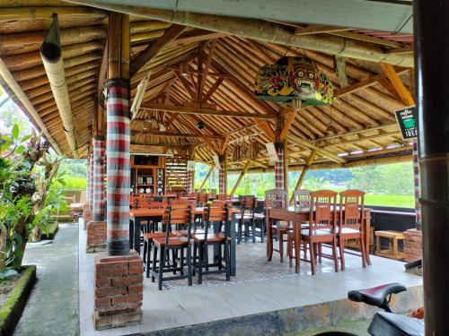 Magical Breeze Cabin في Angsri: مطعم بطاولات وكراسي خشبية تحت سقف خشبي