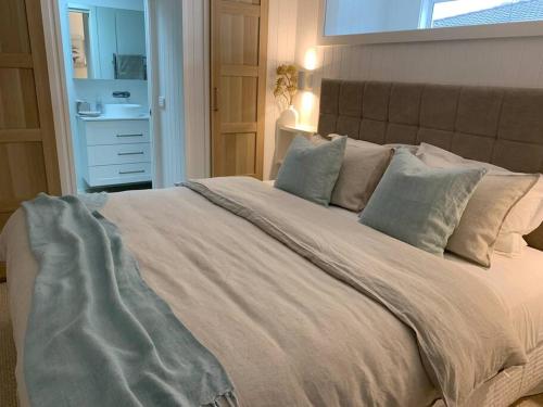 1 dormitorio con 1 cama blanca grande con almohadas en HighTide- luxury apartment, almost on the beach., en Corlette