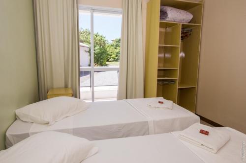 Duas camas num quarto com uma janela em Apartamentos Praia Campeche 50m do mar em Florianópolis