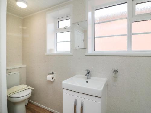 een badkamer met een wastafel, een toilet en een raam bij Cliff Farm No 2 Cottage in Burton Bradstock