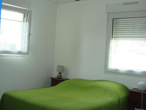 - une chambre avec un lit vert et 2 fenêtres dans l'établissement Maison 3 pièces avec jardin, proche centre et plages, Saint-Denis-d'Oléron - FR-1-246A-339, à Saint-Denis-dʼOléron