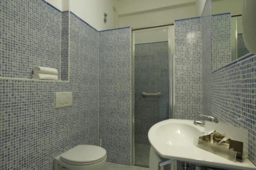 a blue tiled bathroom with a toilet and a sink at Hotel Miramare in Diano Marina