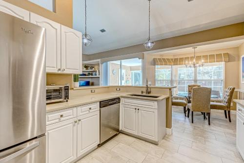 a kitchen with white cabinets and a dining room with a table at R-Time in Sebastian