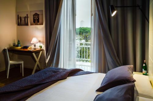 a bedroom with a bed and a window with a desk at Hotel Prestigio in Milano Marittima