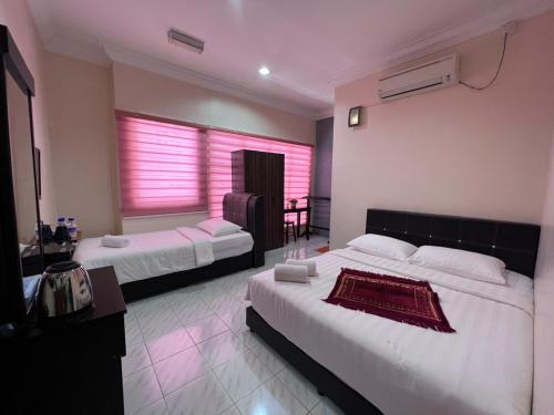 HOTEL RAUDHAH Kerteh في كيرتيه: غرفة فندقية بسريرين ونافذة