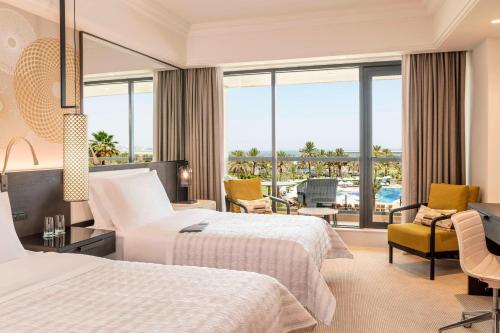 a hotel room with two beds and a balcony at Le Royal Meridien Beach Resort & Spa Dubai in Dubai
