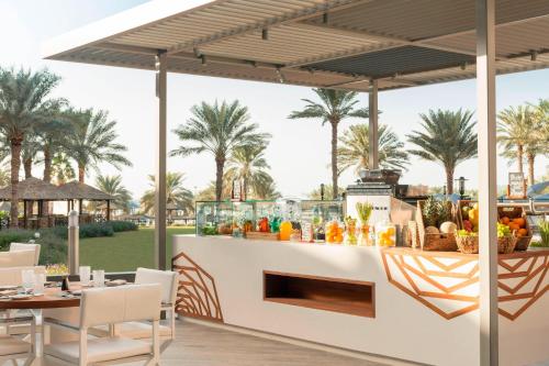 a restaurant with a bar with palm trees in the background at Le Royal Meridien Beach Resort & Spa Dubai in Dubai