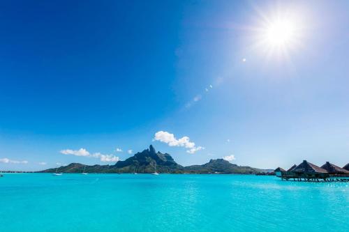 a view of the ocean with mountains in the background at The St. Regis Bora Bora Resort in Bora Bora