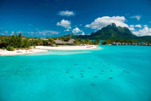 an island in the ocean with a mountain in the background at The St. Regis Bora Bora Resort in Bora Bora
