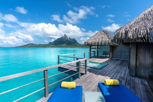 a resort deck with blue benches and the water at The St. Regis Bora Bora Resort in Bora Bora