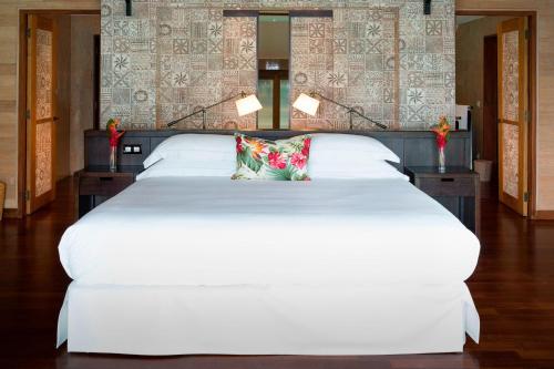 a large white bed in a room with two lamps at The St. Regis Bora Bora Resort in Bora Bora