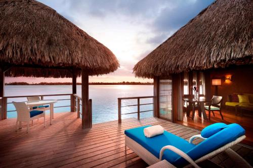 a resort on the water with a table and chairs at The St. Regis Bora Bora Resort in Bora Bora