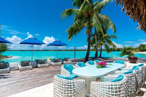 a table and chairs on a deck with a view of the ocean at The St. Regis Bora Bora Resort in Bora Bora
