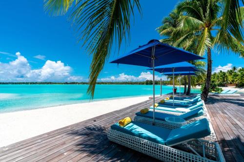 a group of blue chairs and umbrellas on a beach at The St. Regis Bora Bora Resort in Bora Bora