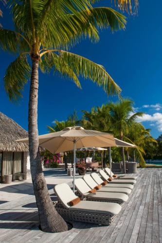 a row of lounge chairs and umbrellas on a beach at The St. Regis Bora Bora Resort in Bora Bora