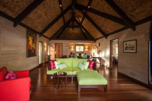 a living room with a green couch and red chairs at The St. Regis Bora Bora Resort in Bora Bora