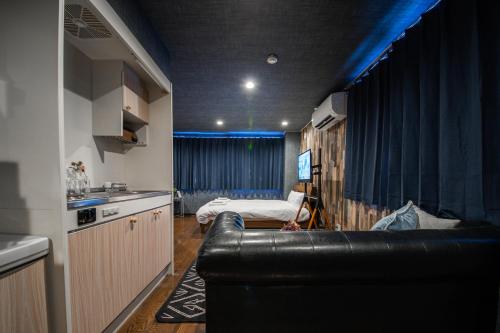 ein Wohnzimmer mit einem schwarzen Ledersofa und einem Bett in der Unterkunft Silk COURT in Chitose