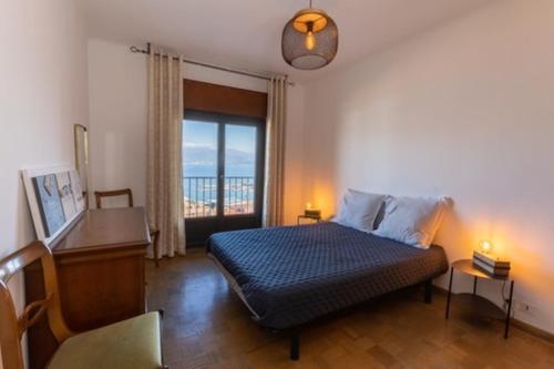 Schlafzimmer mit einem Bett, einem Schreibtisch und einem Fenster in der Unterkunft appartement avec vue mer exceptionnelle in Ajaccio
