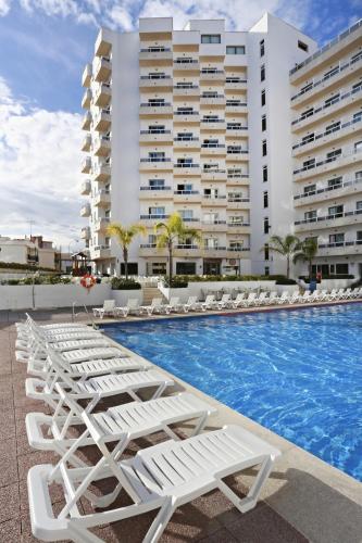 a pool with lounge chairs and a building at Sandos Griego in Torremolinos