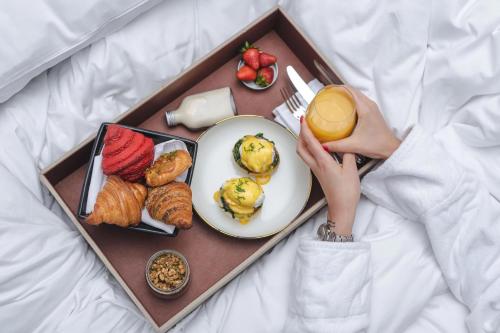 a tray of breakfast food with a person holding a glass of juice at Al Messila, A Luxury Collection Resort & Spa, Doha in Doha