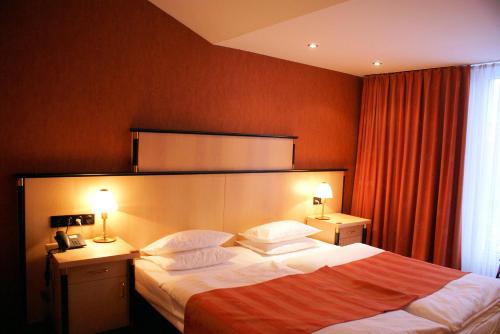 a hotel room with a bed and two lamps at ARVENA Messe Hotel in Nürnberg
