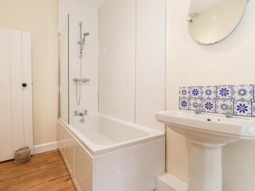 een witte badkamer met een bad en een wastafel bij Irt Cottage in Seascale
