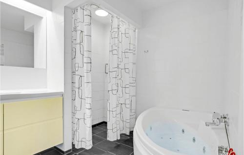 a bathroom with a tub and a shower curtain at 3 Bedroom Cozy Apartment In Ebeltoft in Ebeltoft