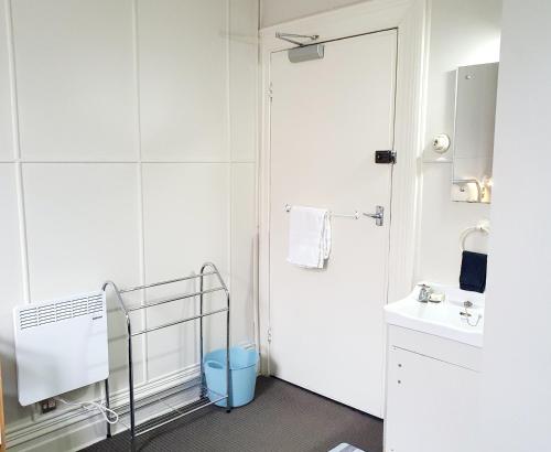 Baño blanco con lavabo y espejo en Extended Stay City Hostel, en Dunedin