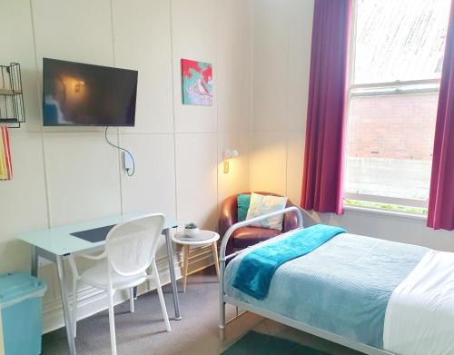una camera con letto, tavolo e scrivania di Extended Stay City Hostel a Dunedin