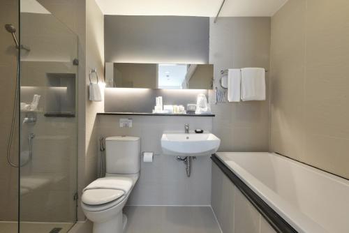a bathroom with a toilet and a sink and a tub at Arize Hotel Sukhumvit in Bangkok