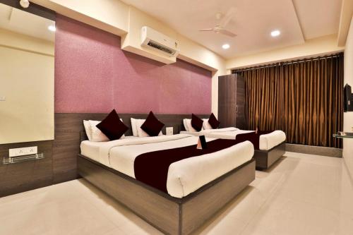 a bedroom with two beds and a purple wall at Hotel Royal Rituals Vesu in Surat