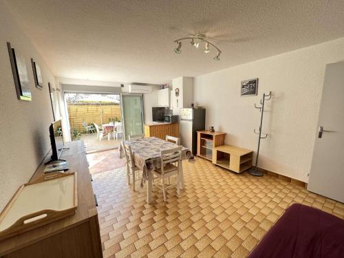 un salon avec une table et une cuisine dans l'établissement Appartement T2 avec Jardin, Climatisation, Parking, et Proche Commerces (Animaux Acceptés) - FR-1-702-43, au Cap d'Agde