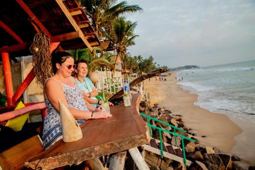two women sitting at a table next to the beach at Brother's Beach Home in Galle