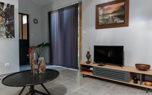 ein Wohnzimmer mit einem TV und einem Tisch in der Unterkunft I love Bergerac Cottage in Bergerac