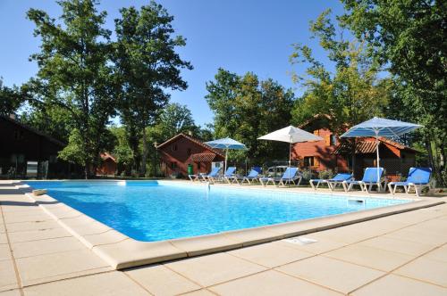 une grande piscine avec chaises et parasols dans l'établissement Résidence Souillac Golf & Country Club, à Lachapelle-Auzac