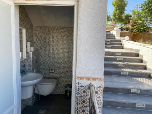 a bathroom with a sink and a toilet and stairs at Golden rays chalet in Madaba