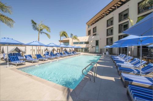 a swimming pool with chairs and blue umbrellas at Legacy Resort Hotel & Spa in San Diego