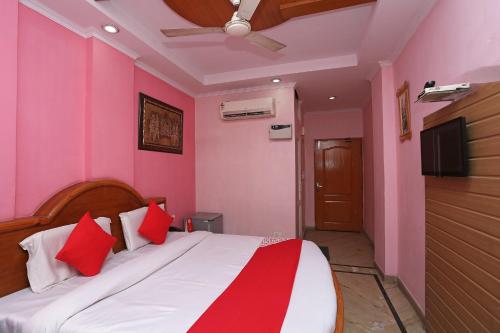 1 dormitorio con paredes rosas y 1 cama con almohadas rojas en OYO Hotel Madhur Regency, en Meerut