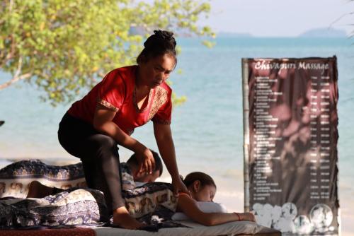 a woman sitting on the beach next to a child at The Tropical Beach Resort in Ko Chang