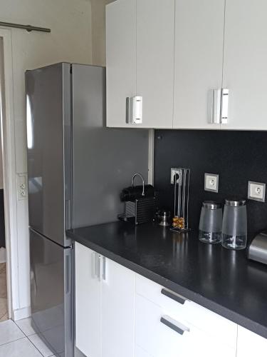 une cuisine avec des armoires blanches et un réfrigérateur en acier inoxydable dans l'établissement Maison Aubergenville Elisabethville, à Aubergenville