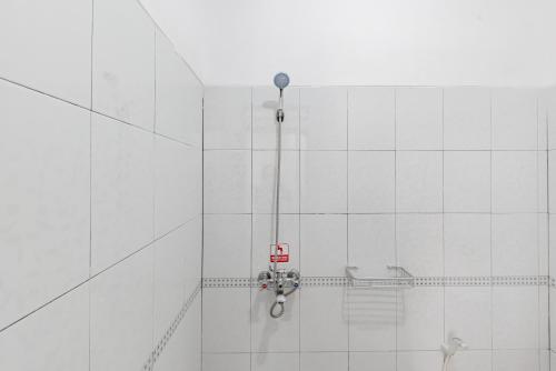 a shower in a white tiled bathroom at Urbanview Hotel My Honai Setrasari by RedDoorz in Bandung