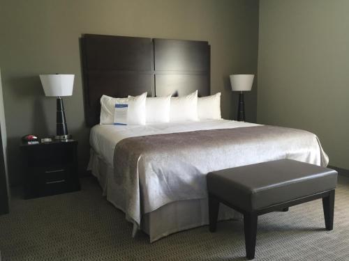 a hotel room with a large bed and a stool at Baymont by Wyndham College Station in College Station