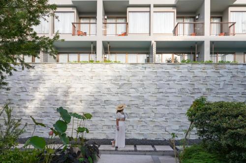 a woman in a hat standing in front of a building at Proud Phuket, Naiyang Beach in Nai Yang Beach