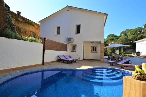 une villa avec une piscine en face d'une maison dans l'établissement Villa Isabel Lloret de mar, à Lloret de Mar