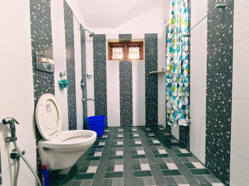 a bathroom with a toilet and a green and white tile floor at White Sands Homestay in Turavūr