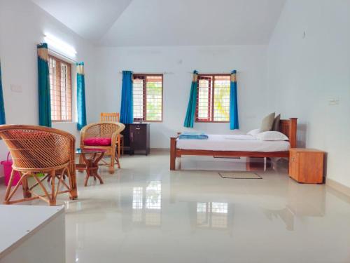 um quarto com uma cama e cadeiras num quarto em White Sands Homestay em Turavūr