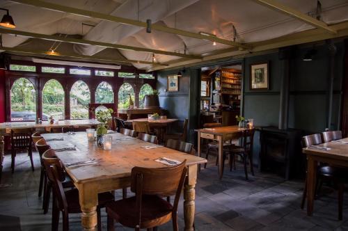 un restaurante con mesas y sillas de madera y ventanas en Buitengoed De Uylenburg, en Delft