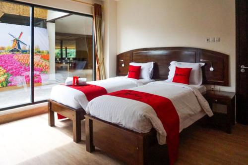 een slaapkamer met 2 bedden met rode kussens en een raam bij RedDoorz near Londa Toraja in Madandan