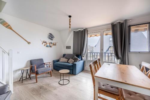 salon z niebieską kanapą i stołem w obiekcie Duplex du Littoral - Vue mer w mieście Villers-sur-Mer