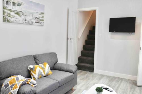a living room with a gray couch and a staircase at Contemporary & Stylish House . FREE Parking in Beeston Hill